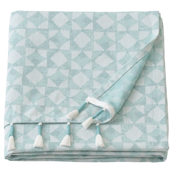 Un plaid GOKVÄLLÅ plié. Il est bleu clair avec des accents blancs, avec un motif géométrique et des pompons faits à la main le long du bord.