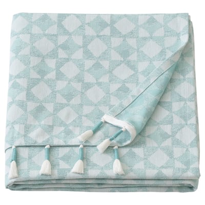 Un plaid GOKVÄLLÅ plié. Il est bleu clair avec des accents blancs, avec un motif géométrique et des pompons faits à la main le long du bord.