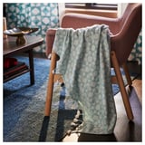 Une couverture douillette à motifs bleus et blancs avec des glands drapés sur une chaise rose.
