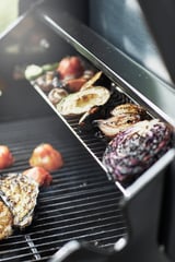 Un barbecue à gaz GRILLSKÄR avec divers légumes grillés.