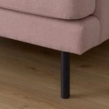 Gros plan de la jambe du canapé rose sur le plancher en bois. Tissu doux, conception robuste.