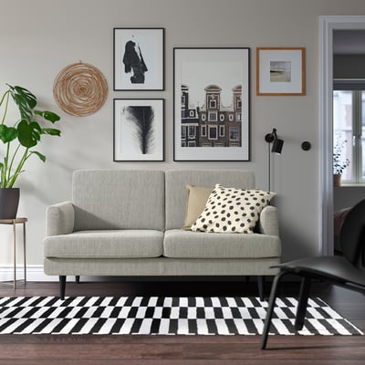 Salon moderne avec canapé GRILLSTORP, galerie d’art, plante et table d’appoint.