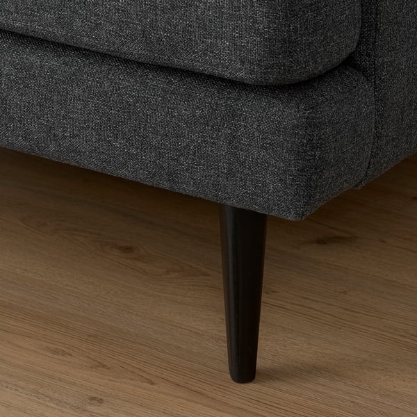 Gros plan du canapé GRILLSTORP gris foncé sur un plancher de bois franc, présentant un design de pieds élégant et un tissu durable.