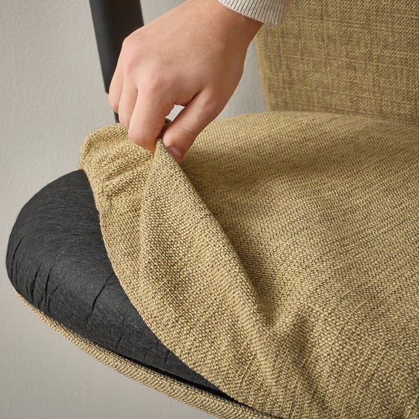 Support lombaire réglable sur chaise de bureau ergonomique beige. La main appuie sur le bouton de l’accoudoir pour un confort personnalisé.