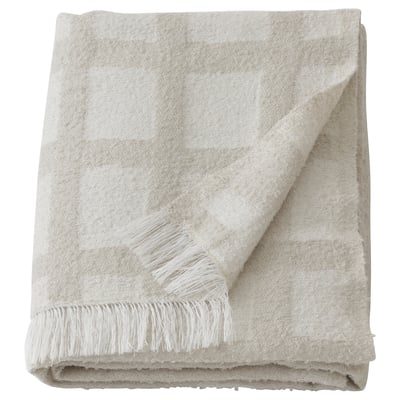 Un plaid GRÖNKNAVEL beige avec des franges sur les bords, fabriqué à partir de polyester 100 % recyclé.