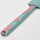 Une spatule en silicone pliable en turquoise et rose, idéale pour racler les bols.