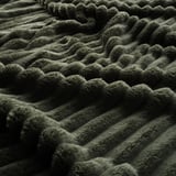 Couverture verte, douce et moelleuse en gros plan. Texture profonde, sensation de luxe.