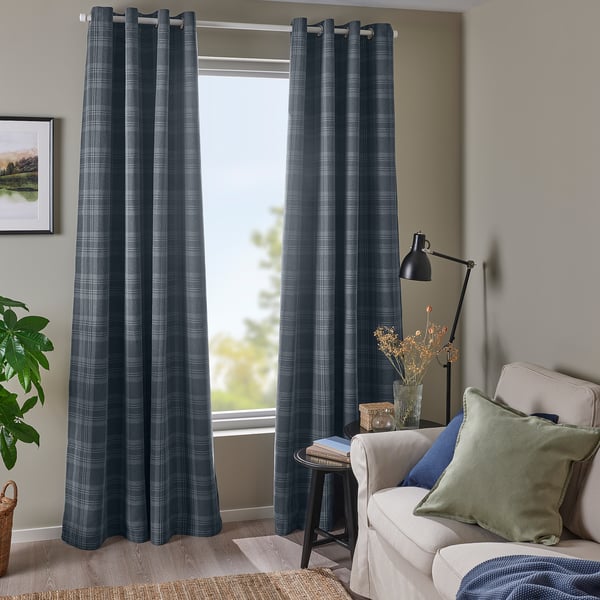 Chambre lumineuse avec des rideaux en tartan gris foncé HÄGGVECKMAL, des oreillers verts et une chaise confortable.