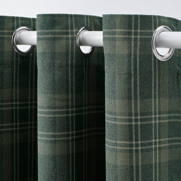 Des rideaux en tartan vert foncé avec œillets pendent soigneusement, offrant un assombrissement et une intimité.