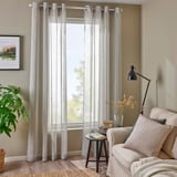 Rideaux gris au sol dans un salon confortable avec canapé et lampe.
