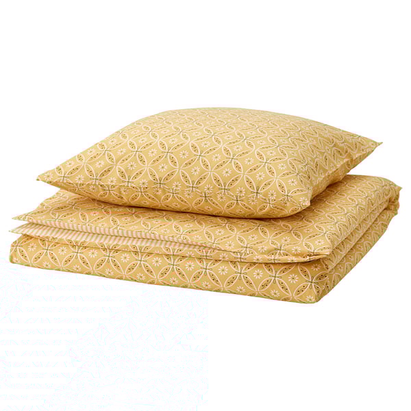 Parure de lit HAMNSENAP jaune pliée à motifs floraux et rayés.