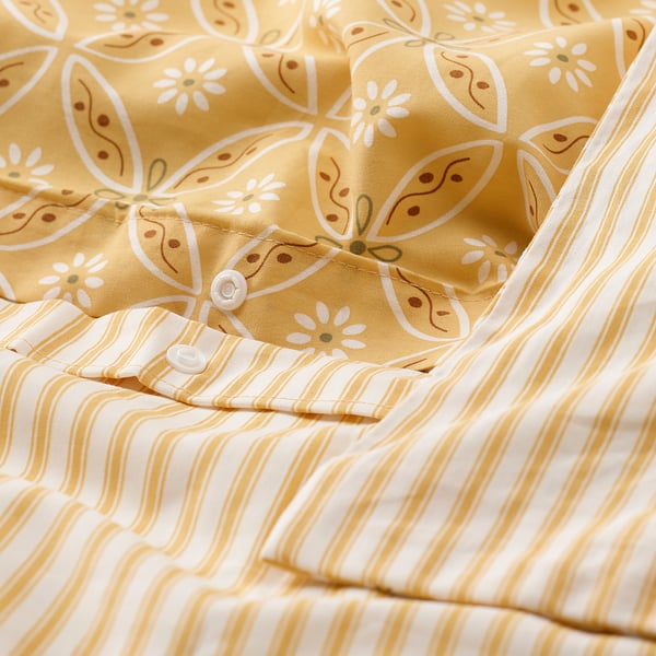 Ensemble de couette HAMNSENAP jaune moutarde à motif floral, avec un design réversible et un tissu respirant, montré sur la photo.
