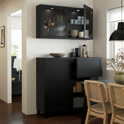 Cuisine moderne avec armoires noires, présentoir en verre, chaises en osier, bol en bois, suspension.