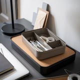 Organisateur de bureau en liège gris et métal avec compartiments, contenant des fournitures de bureau.