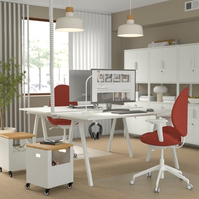 Espace de travail moderne avec des chaises ergonomiques rouges HATTEFJÄLL, des bureaux blancs et des suspensions ; plantes par fenêtre.