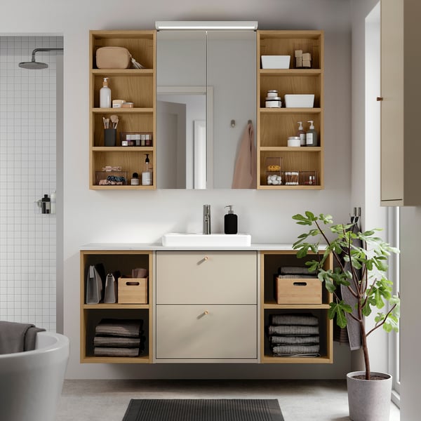 Rangement de salle de bain HAVBÄCK beige avec lavabo, miroir, plante.