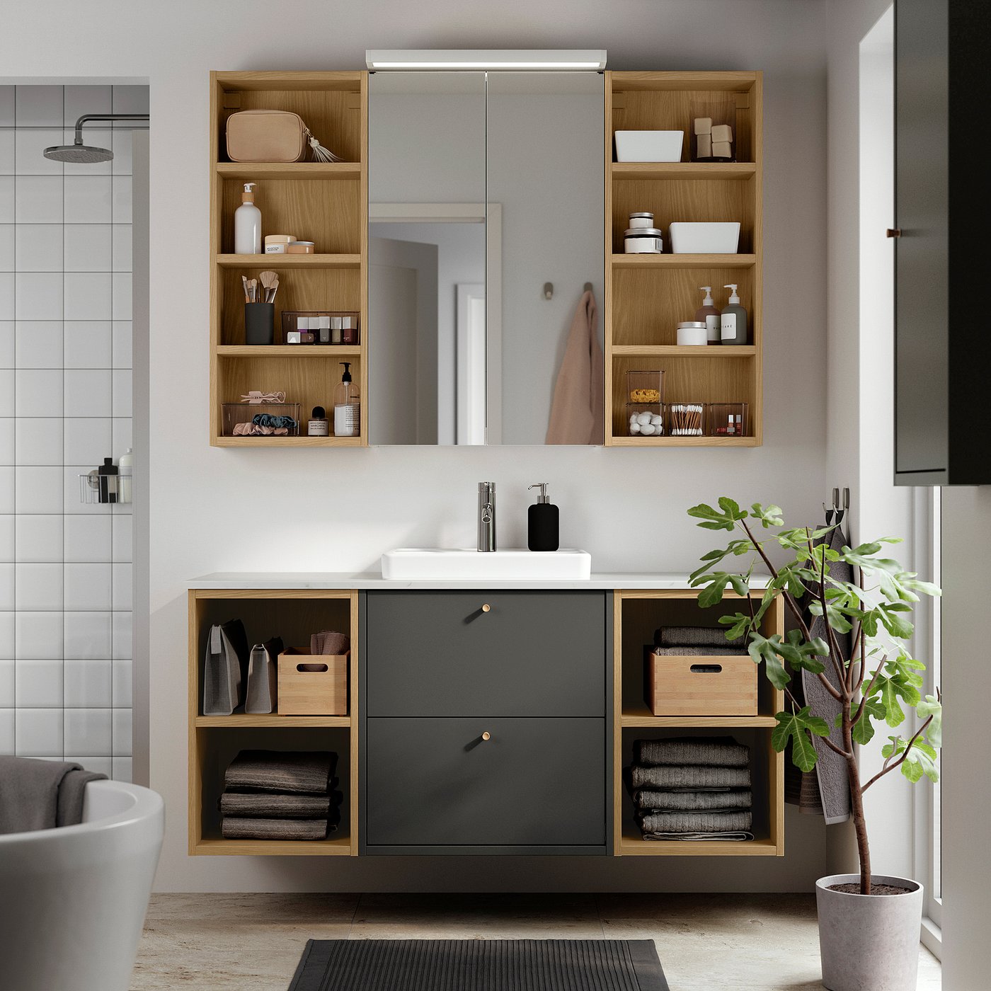 Salle de bain moderne avec meuble-lavabo gris foncé et bois clair, miroir et étagères ouvertes. Plantes et serviettes illustrées.