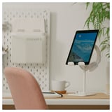Espace de travail moderne avec support d’iPad, chaise, tasse et plante.