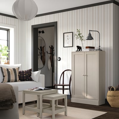 Chambre moderne avec des murs rayés gris clair, un canapé blanc, une armoire en bois et une suspension élégante.