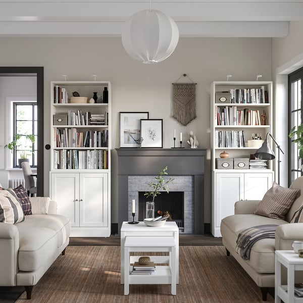 Salon moderne avec des meubles de rangement HAVSTA blancs, des canapés gris clair, une cheminée à cadre noir et un décor neutre.