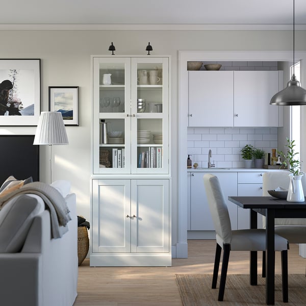 Armoire HAVSTA grise avec verrerie dans le salon moderne avec canapé et cuisine.