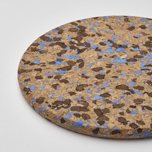 Support rond en liège avec des points bleus sur une surface blanche.