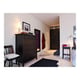 Chambre avec meubles en bois sombre : coffre, chaise, armoire, tapis, lampe, miroir et placard.