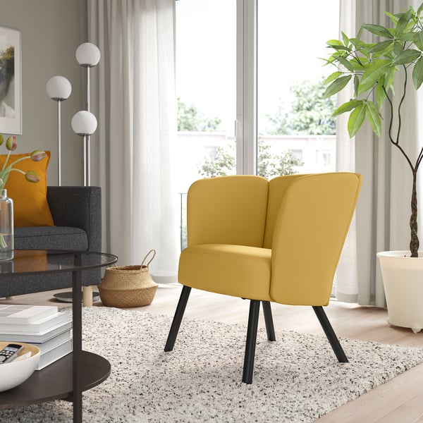 Salon moderne avec fauteuil HERRÅKRA jaune moutarde, canapé gris, plante et lampes. Décor lumineux et minimaliste.