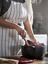 Femme cuisinant dans la cuisine avec un tablier rayé.