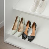 Étagères blanches avec deux paires de talons hauts, l’une verte et l’autre noire, pour un rangement organisé.