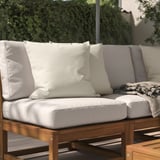 Un coussin d’extérieur blanc sur un banc en bois, apportant confort et style.