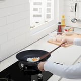 Cuisson de l’œuf au plat dans une poêle avec une spatule. Le comptoir de la cuisine a des ingrédients.