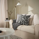 La housse de coussin idalinena au motif floral blanc et noir, ajoute une touche de fraîcheur au canapé. Sa taille complète le décor environnant.