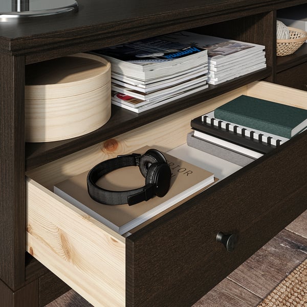 Bureau en bois sombre avec tiroir, étagères ouvertes contenant des livres et des écouteurs.