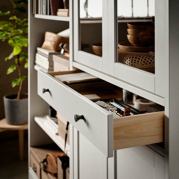 Armoire blanche avec portes vitrées, tiroir en bois ouvert, révélant des fournitures de bureau.