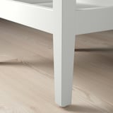 Pied de table en bois blanc moderne sur plancher en bois clair, présentant un design élégant et une construction robuste.
