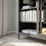 Étagère avec portes coulissantes en verre pour livres, éloignant la poussière. La conception en verre trempé et en métal offre une durabilité et une sensation d’aération.