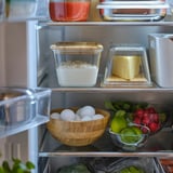 Réfrigérateur ouvert avec des récipients transparents contenant des flocons d’avoine, du beurre et des fruits.