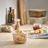 Le panier en maille blanche IKEA 365+ peut contenir des croissants, petits, posé sur une table en bois avec divers articles de cuisine.