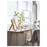 Bureau moderne avec bois clair et chaise grise ; fleurs, lampe et miroir ; Chambre lumineuse et bien rangée.