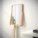 Miroir mural avec étagère suspendue pour les accessoires. Cadre en bois clair, pièce réfléchissante.