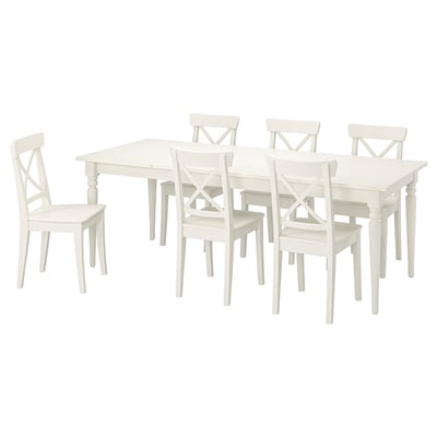 Table à manger et chaises en bois blanc avec des dossiers hauts et des motifs croisés, design classique, adapté pour six personnes.