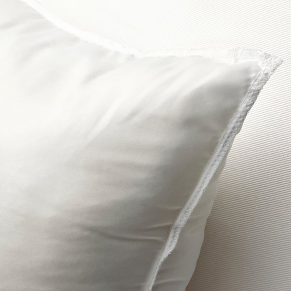 Un gros plan d’un coussin blanc moelleux, mettant en valeur son tissu doux et texturé et son design dodu et invitant.