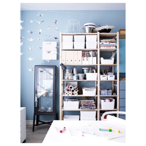 Chambre bleue avec rangement IVAR, étagères, fournitures d’art, grues en papier, armoire noire, table blanche.