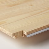 Gros plan sur une surface en bois lisse et léger, mettant en valeur le grain naturel et la qualité de l’artisanat.