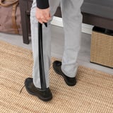 Personne utilisant le chausse-pied sur le tapis près du banc avec un sac.