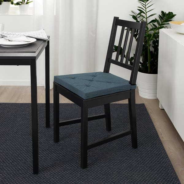 Chaise de salle à manger noire moderne avec coussin d’assise bleu, positionnée à côté de la table avec réglage de l’assiette. Dimensionné pour s’adapter à une salle à manger standard.