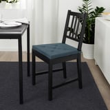 Chaise de salle à manger noire moderne avec coussin d’assise bleu, positionnée à côté de la table avec réglage de l’assiette. Dimensionné pour s’adapter à une salle à manger standard.