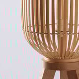 Lampe en bambou fabriquée à la main sur un support en bois, émettant une lumière douce et chaude.