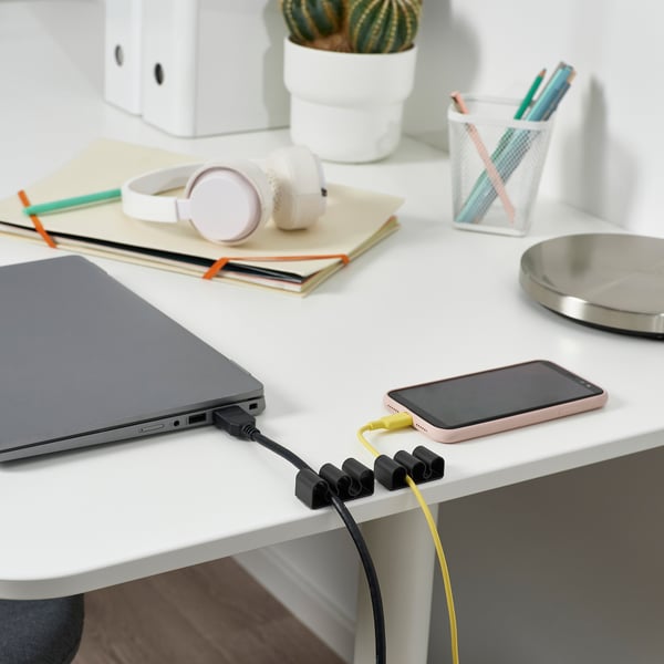 Bureau avec ordinateur portable, recharge du téléphone avec des porte-câbles KALKSTUFF pour garder les cordons bien rangés.